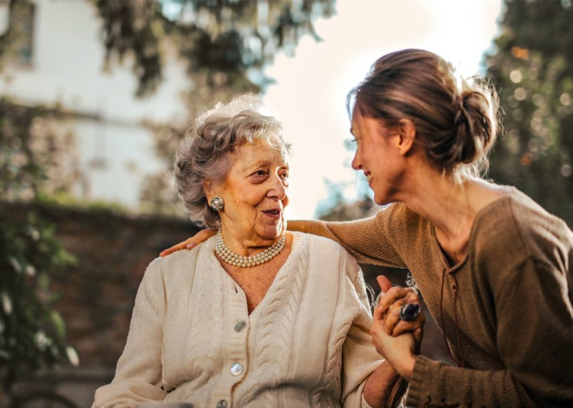 Image of female care provider gently assisting elderly woman