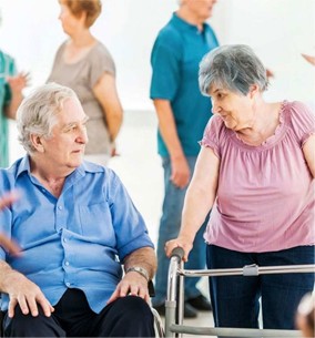 Image of an elderly couple connecting at a community group, one using a walking frame for mobility support