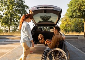Image of an NDIS support worker helping a wheelchair user load their car for a day out with their dog